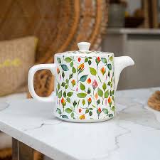 Ceramic teapot with fresh herbs and botanical accents